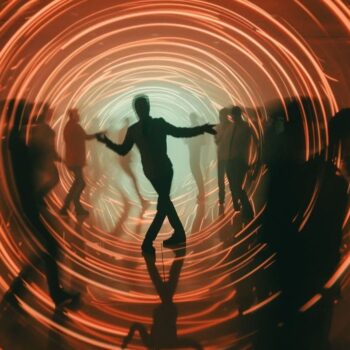 Silhouetted people dancing in a vibrant tunnel with dynamic orange light rings creating a sense of motion and energy.