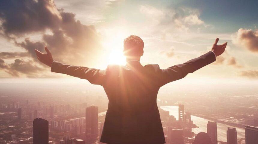 Businessman with arms raised facing sunrise over city skyline expressing success and ambition