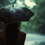 Person holding umbrella in rain with wet hair back view
