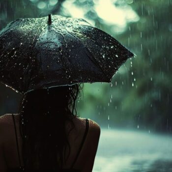 Person holding umbrella in rain with wet hair back view