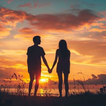 Couple holding hands against sunset sky with clouds