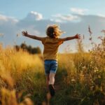 Child running joyfully through a golden field at sunset with arms outstretched.