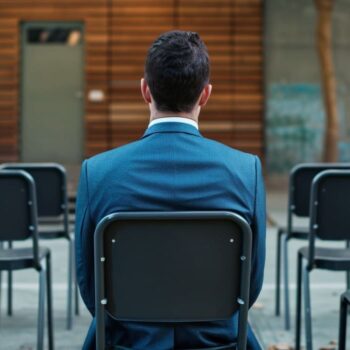 Businessman sitting alone amidst empty chairs outdoors