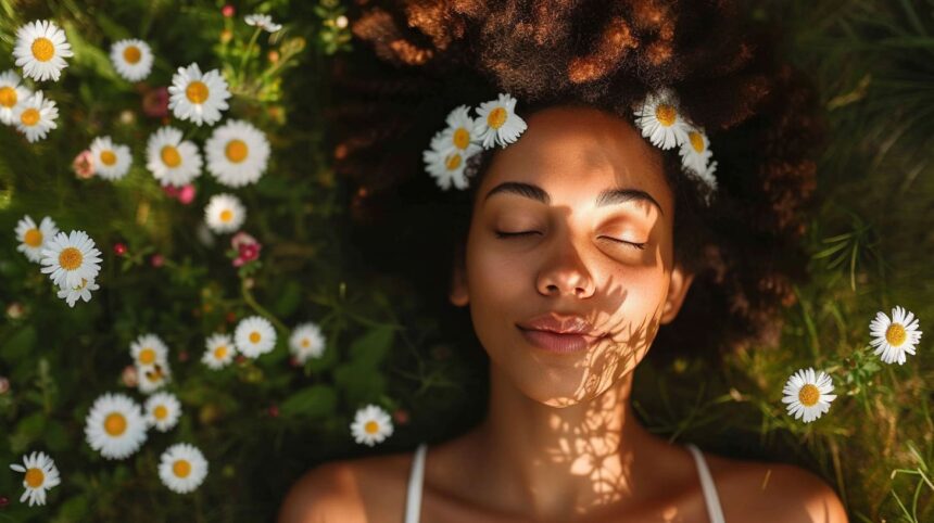 Young woman relaxing in a field of daisies with sunlight casting shadows on her face.